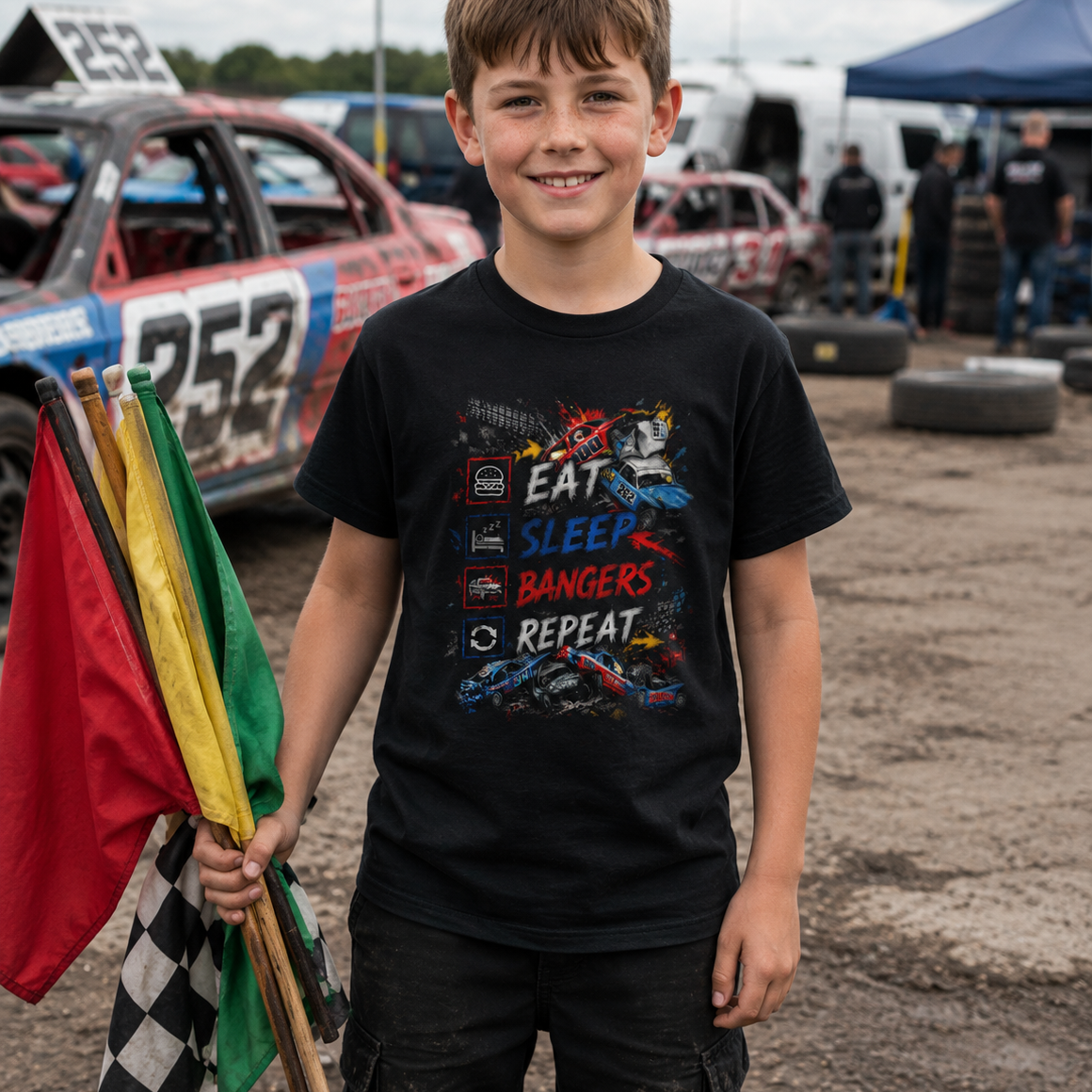 Young boy wearing Eat Sleep Bangers Repeat kids banger racing t-shirt in black while holding racing flags at a banger racing event