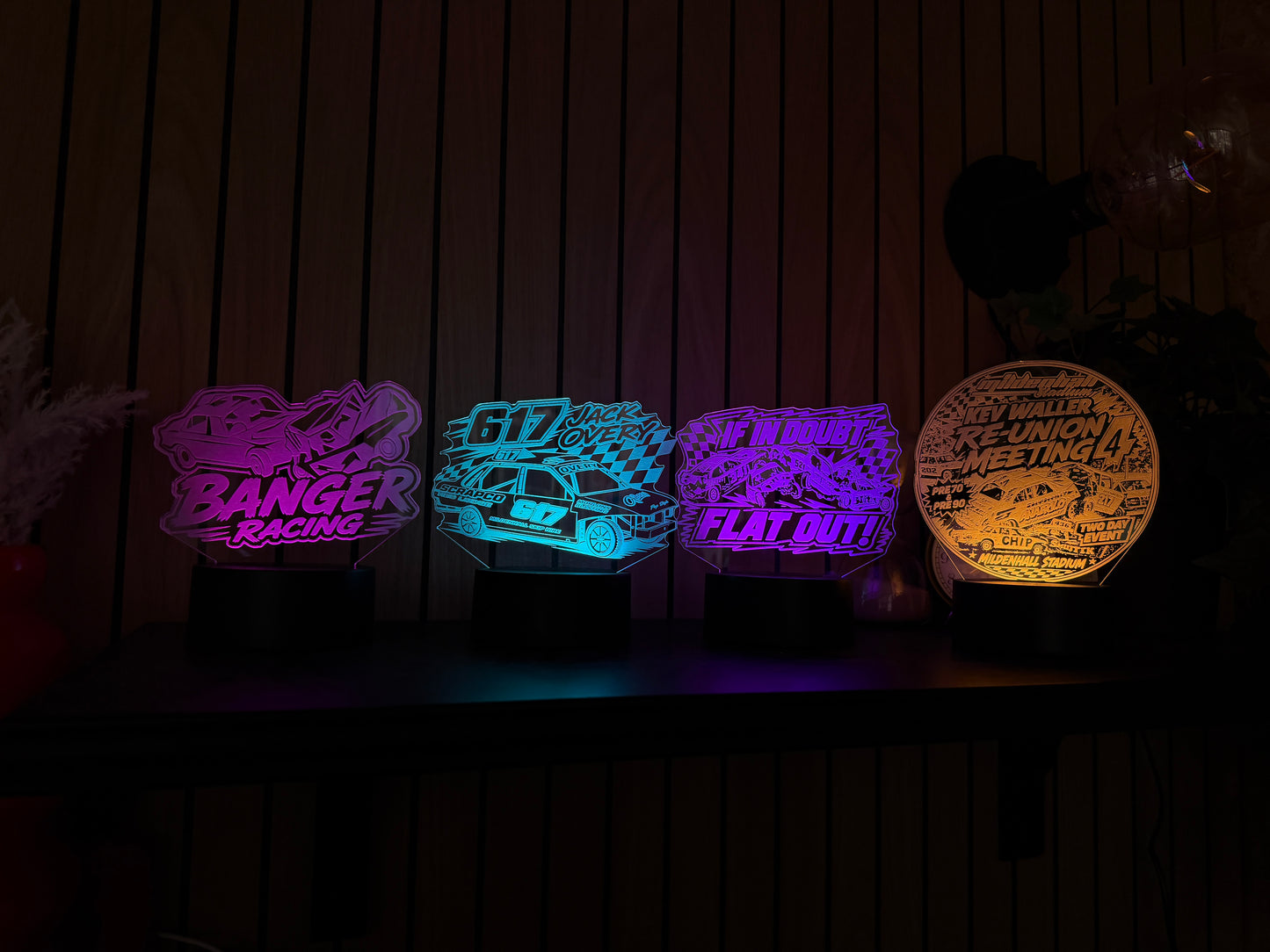 Four colorful LED signs on a wooden surface with a dark background