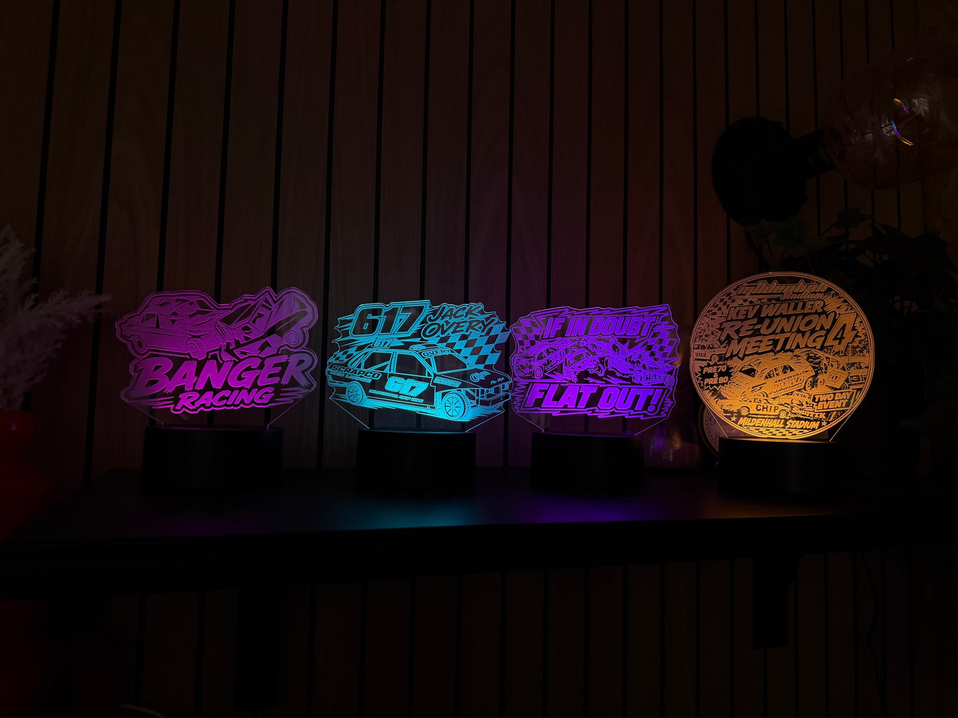 Four colorful LED signs on a wooden surface with a dark background